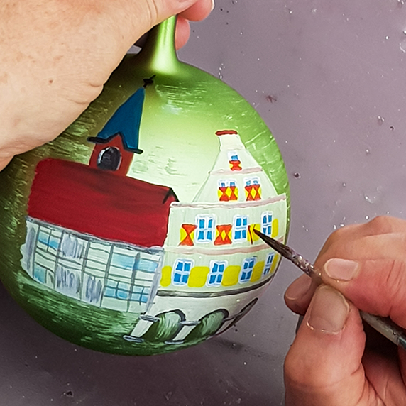 Painting at our workshop | Glavena Painter drawing church on ornament during workshop